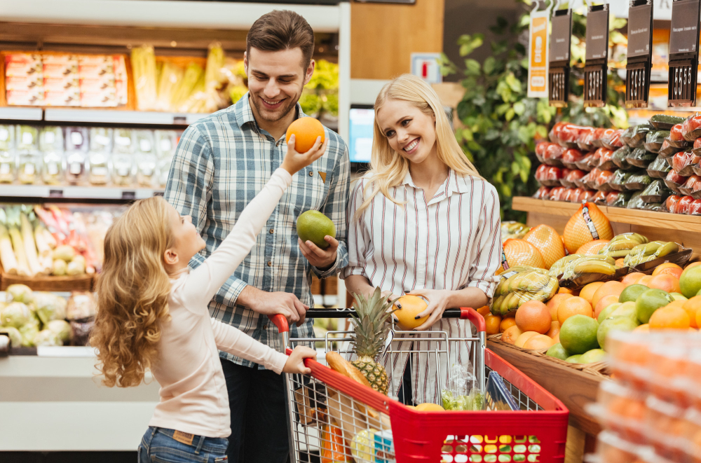 Mladi bračni par i njihova ćerka kupuju zdrave namirnice u supermarketu. 